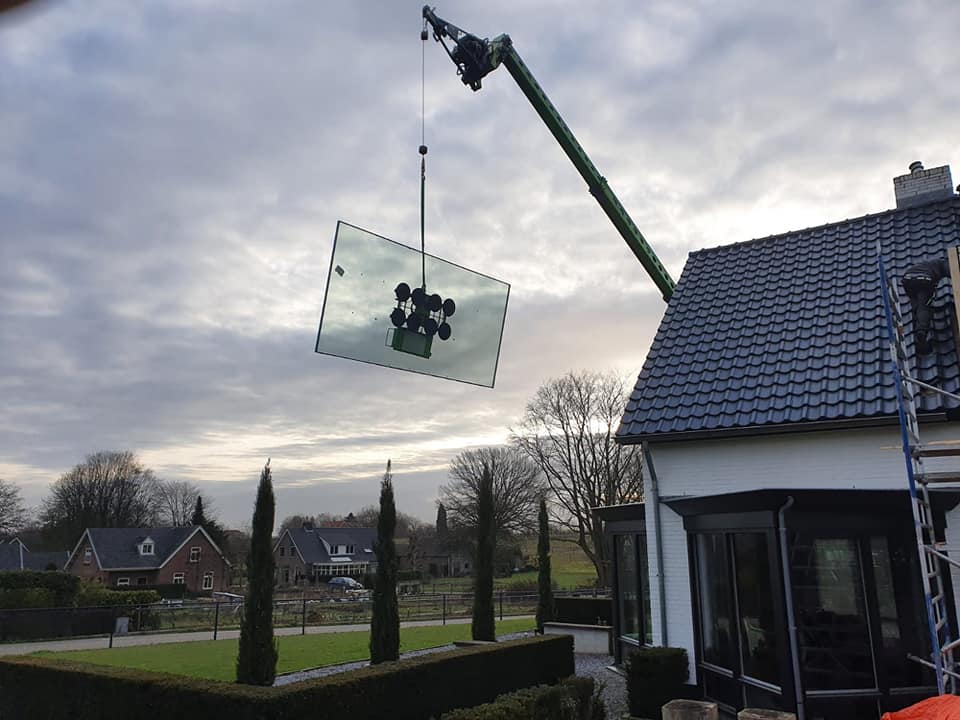 Van Leth Schilderwerken - Groot formaat glasplaat met een kraan op zijn plek gehesen bij een particuliere woning.
