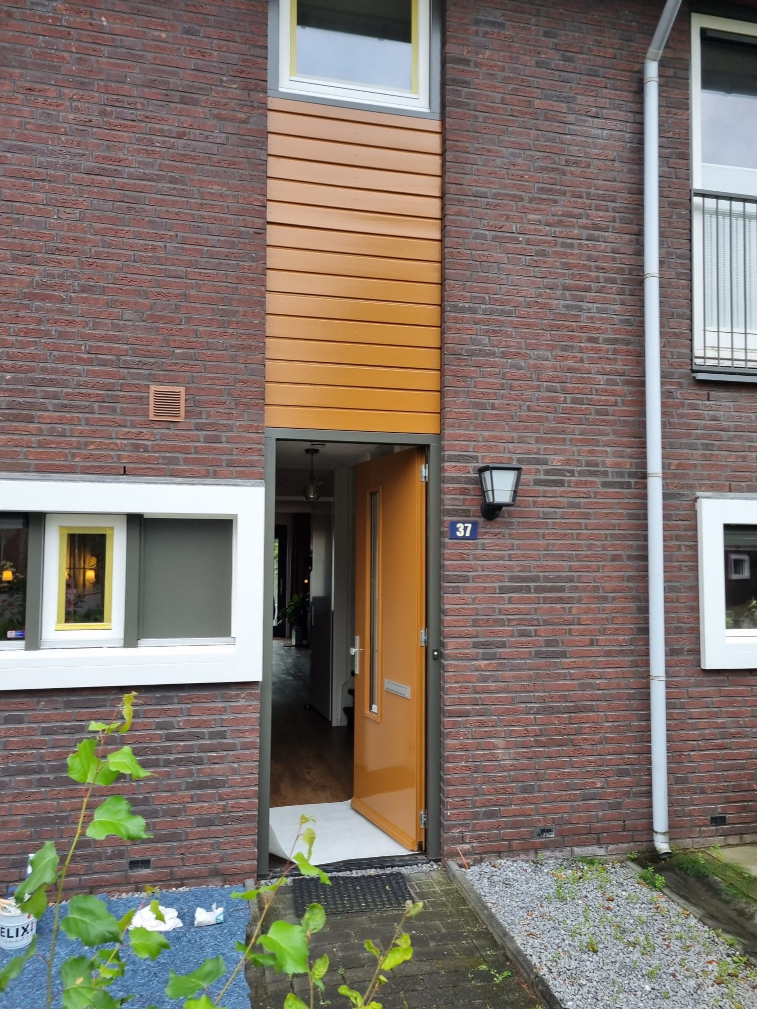 Van Leth Schilderwerken - Voordeur en houten bekleding boven de entree geschilderd in een opvallende kleur. Stijlvol en duurzaam.